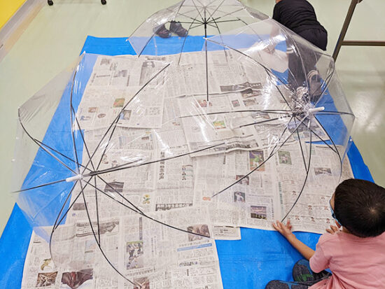 新聞紙は傘より大きく広げて汚れ防止